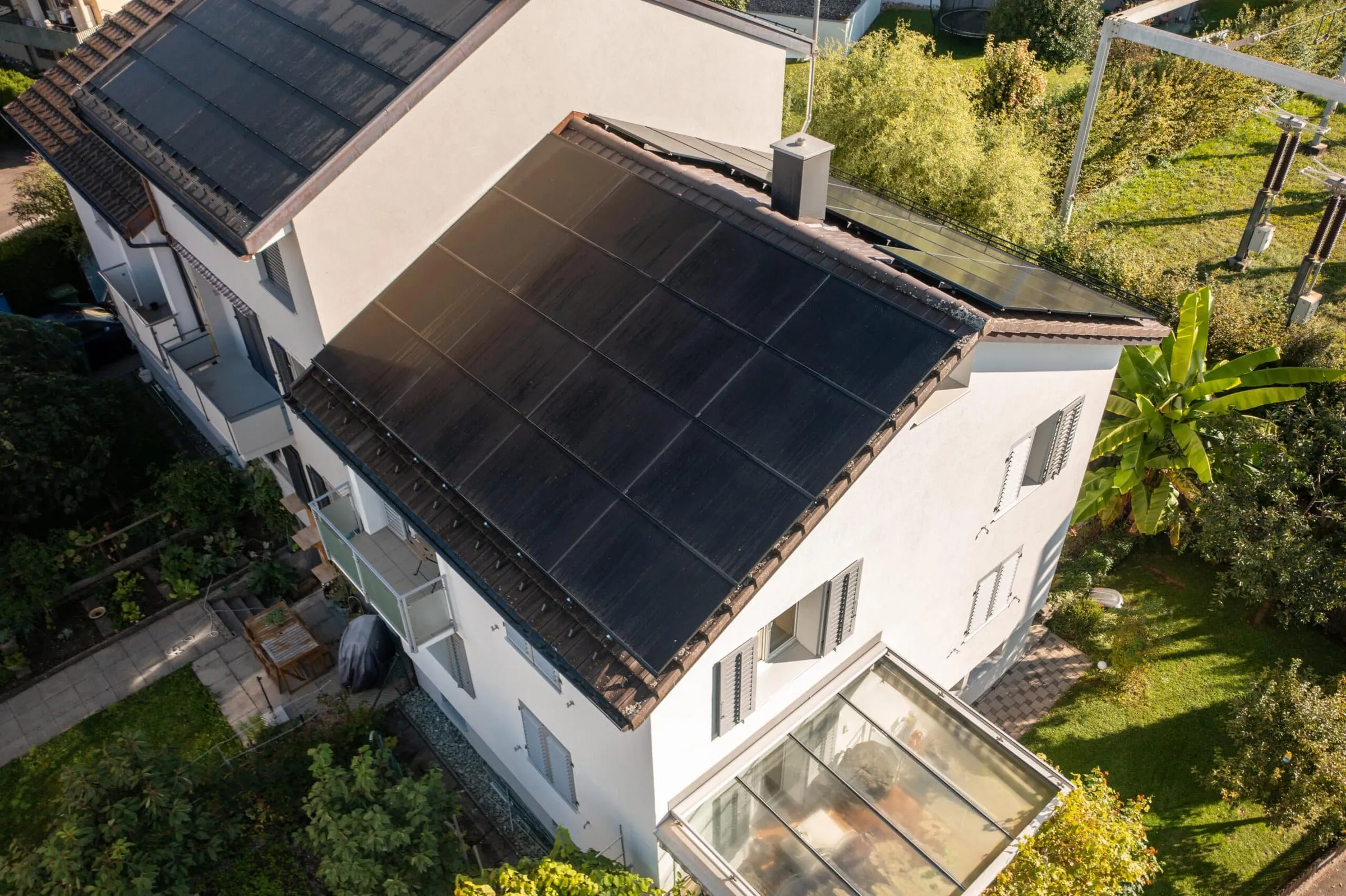 Einfamilienhaus mit schwarzen Solarmodulen auf dem Ziegeldach, Drohnenaufnahme eines Projekts von Solar Innovation.