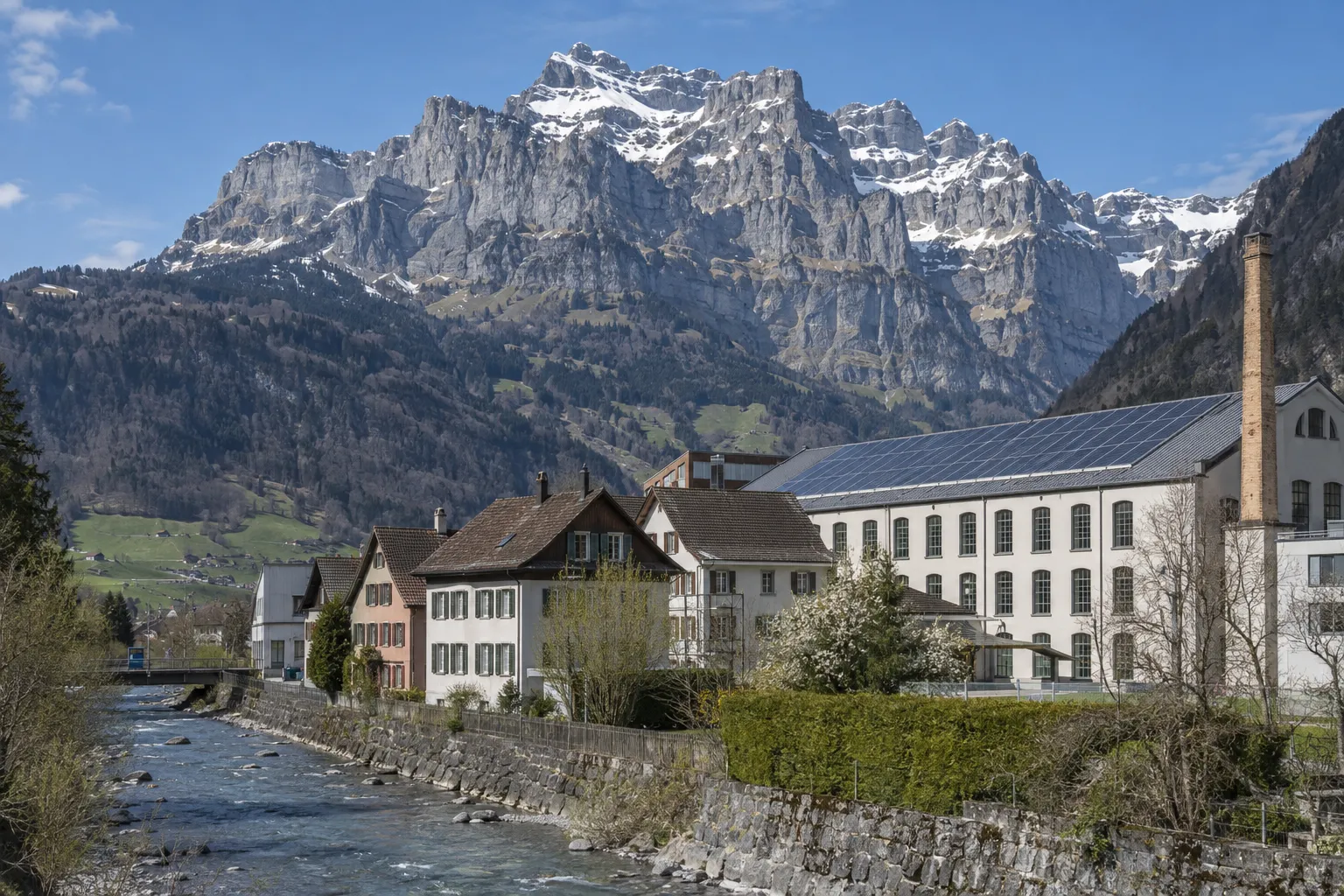 Linthtal im Kanton Glarus mit einem Gewerbebau mit Solardach unter dem Glärnisch.