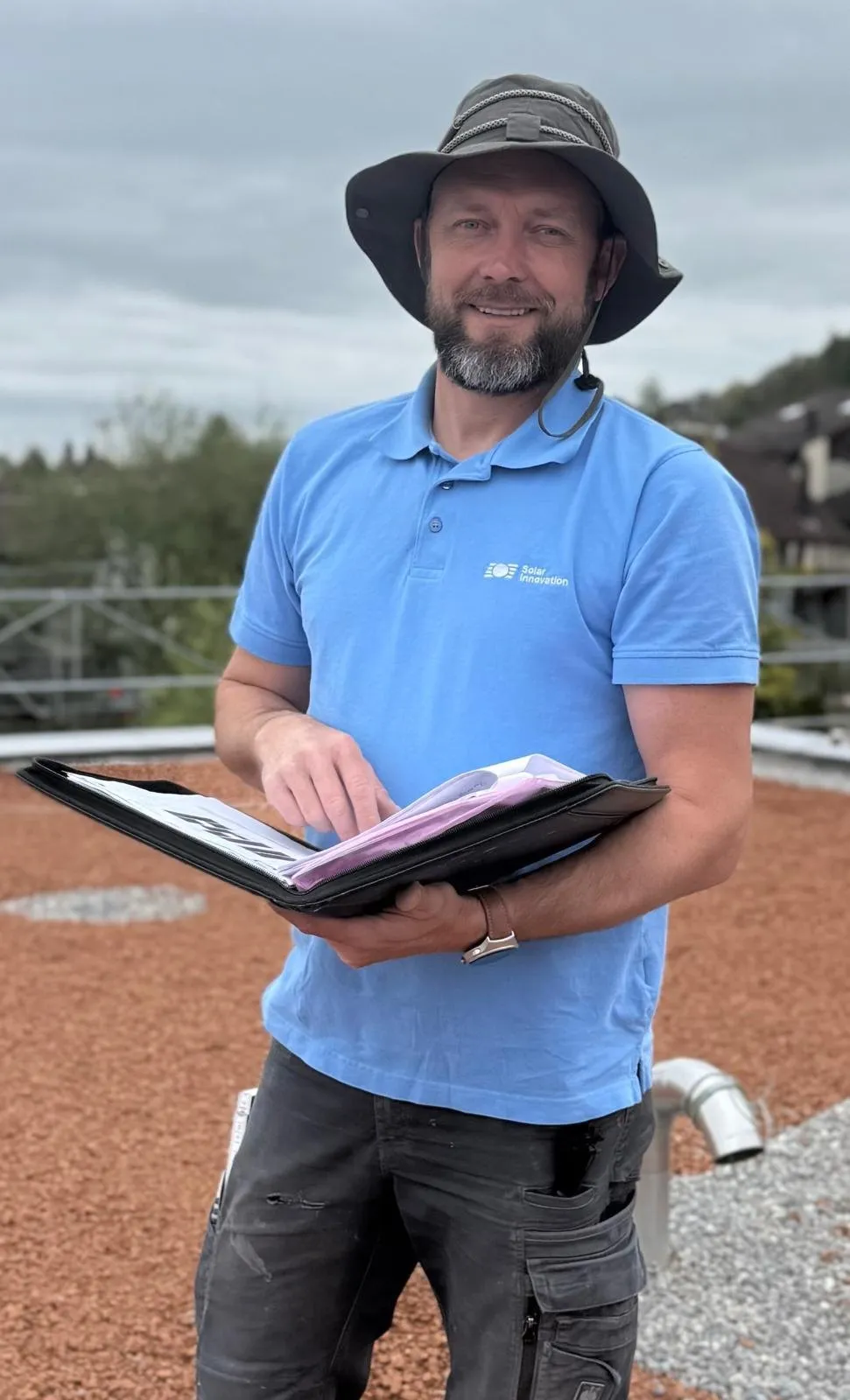Zarko Mitrovic, Projektleiter Solar, auf einem Flachdach mit den Projektunterlagen.